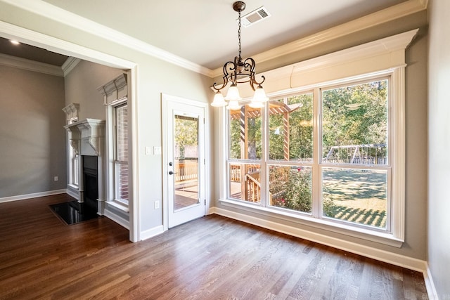 unfurnished dining area with dark wood-type flooring, crown molding, and a chandelier