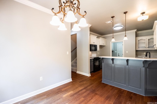 kitchen featuring white cabinets, dark hardwood / wood-style flooring, a kitchen bar, ornamental molding, and black appliances