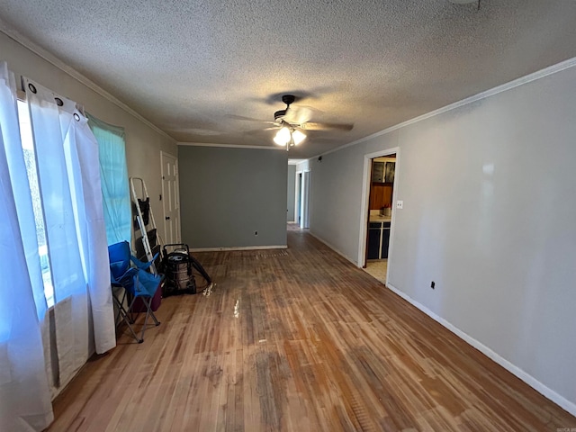 unfurnished living room featuring ceiling fan, hardwood / wood-style flooring, a textured ceiling, and ornamental molding