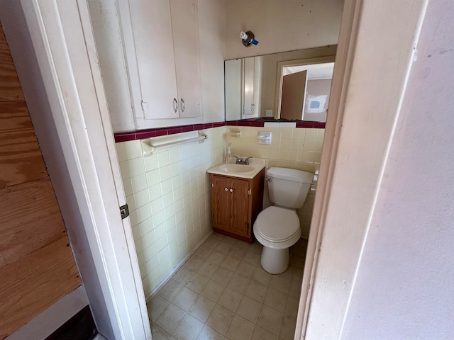 bathroom with vanity, toilet, and tile walls