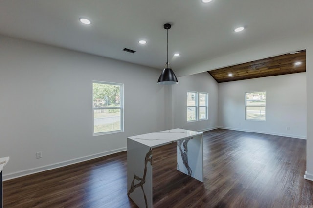 kitchen with light stone counters, dark wood-type flooring, vaulted ceiling with beams, and decorative light fixtures