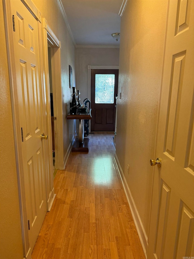 hall with light hardwood / wood-style floors and ornamental molding