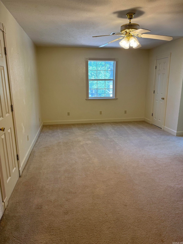 spare room featuring a textured ceiling, light colored carpet, and ceiling fan