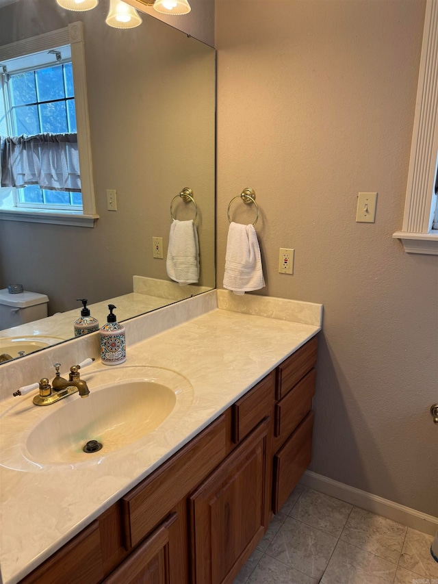 bathroom with toilet, vanity, and tile patterned flooring