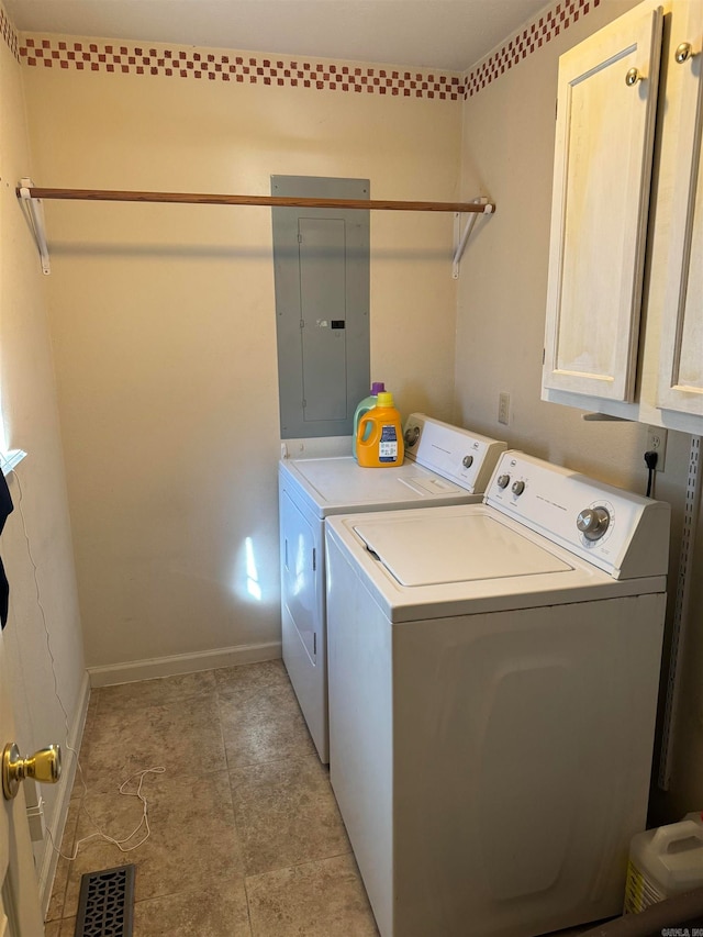 clothes washing area featuring electric panel, washing machine and clothes dryer, and cabinets