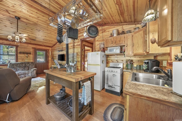 kitchen featuring lofted ceiling, wood walls, sink, and white appliances