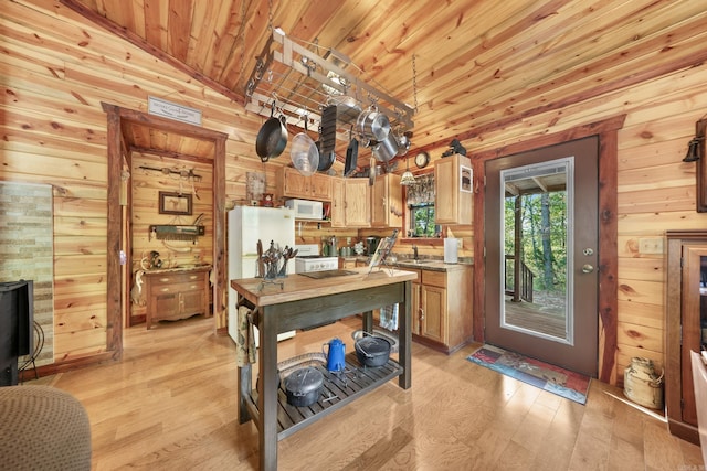 kitchen featuring wooden walls, vaulted ceiling, white appliances, and light hardwood / wood-style floors