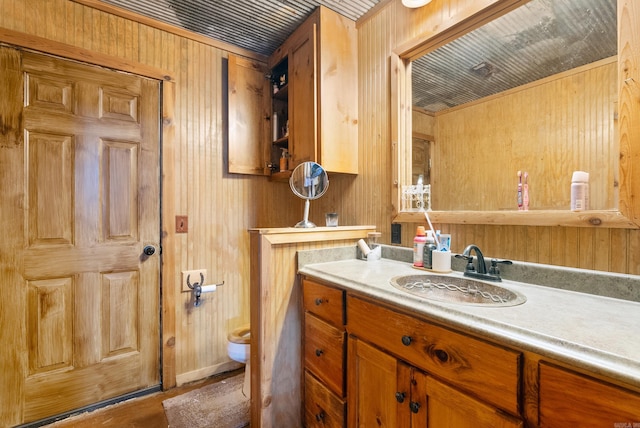 bathroom featuring vanity, toilet, hardwood / wood-style flooring, and wooden walls