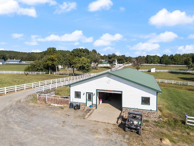 exterior space featuring a garage, a lawn, and a rural view