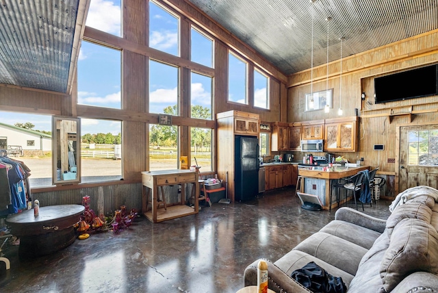 living room featuring a towering ceiling and wooden walls