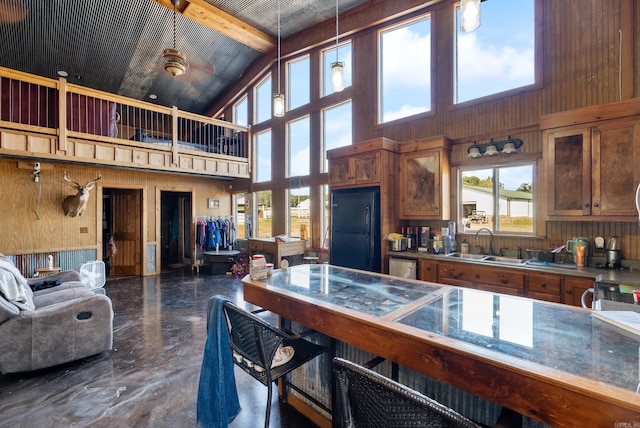 kitchen featuring beam ceiling, black refrigerator, sink, pendant lighting, and high vaulted ceiling