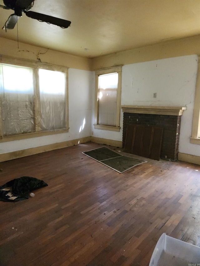 interior space featuring a brick fireplace, ceiling fan, and dark hardwood / wood-style flooring