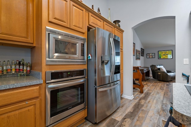 kitchen featuring dark wood-type flooring, appliances with stainless steel finishes, and vaulted ceiling