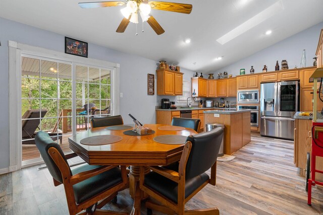 dining room with light hardwood / wood-style flooring, vaulted ceiling, and ceiling fan