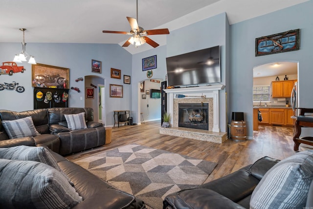 living room with high vaulted ceiling, sink, ceiling fan with notable chandelier, and hardwood / wood-style floors