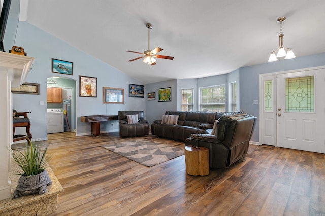 living room featuring washer / clothes dryer, ceiling fan with notable chandelier, vaulted ceiling, and dark hardwood / wood-style floors