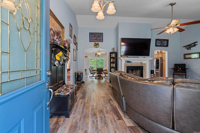 living room featuring vaulted ceiling, ceiling fan with notable chandelier, and light wood-type flooring