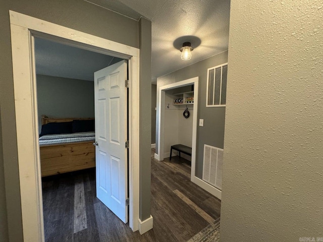 hallway with dark wood-type flooring and a textured ceiling