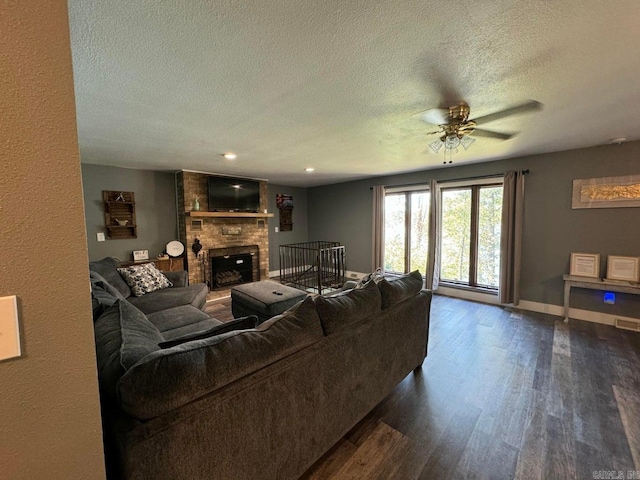 living room featuring a brick fireplace, a textured ceiling, ceiling fan, and dark hardwood / wood-style flooring