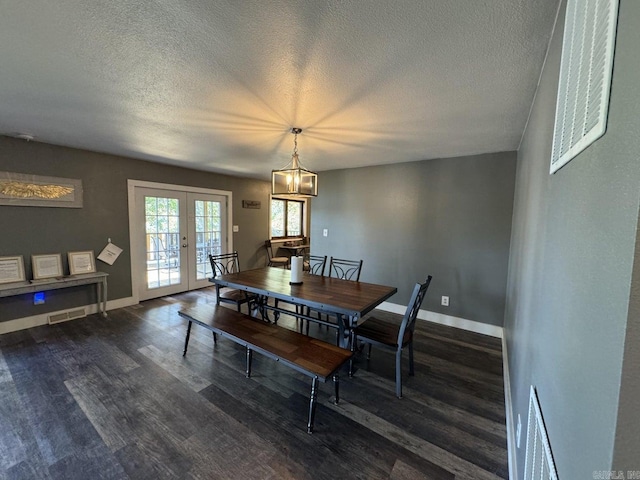 dining area featuring an inviting chandelier, french doors, dark hardwood / wood-style floors, and a textured ceiling