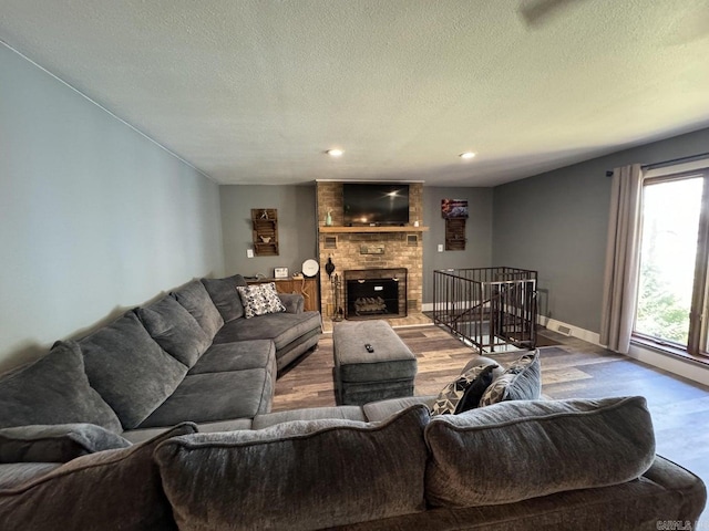 living room featuring hardwood / wood-style floors, a textured ceiling, and a brick fireplace