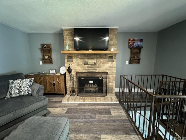 living room featuring hardwood / wood-style flooring, a textured ceiling, and a brick fireplace