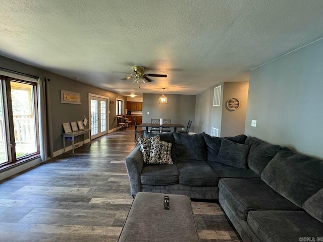 living room with a textured ceiling, dark hardwood / wood-style floors, and ceiling fan