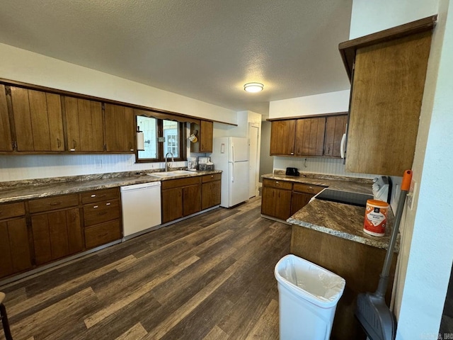 kitchen featuring white appliances, a textured ceiling, sink, and dark hardwood / wood-style flooring