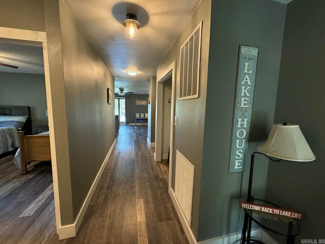 hallway featuring a textured ceiling and dark hardwood / wood-style floors