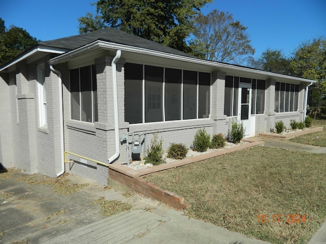 view of front facade with a sunroom and a front lawn