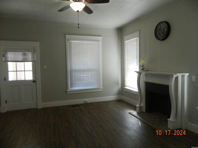 unfurnished living room featuring dark wood-type flooring, ceiling fan, ornamental molding, and plenty of natural light