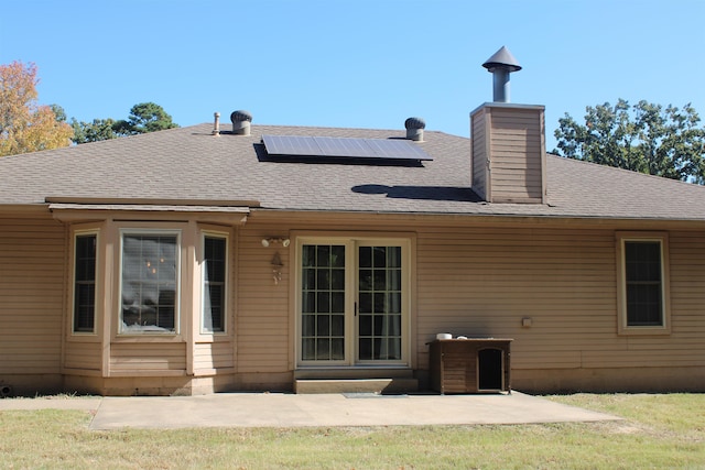 rear view of house with a yard and solar panels