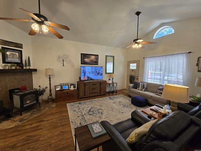 living room with a wood stove, ceiling fan, dark wood-type flooring, and vaulted ceiling