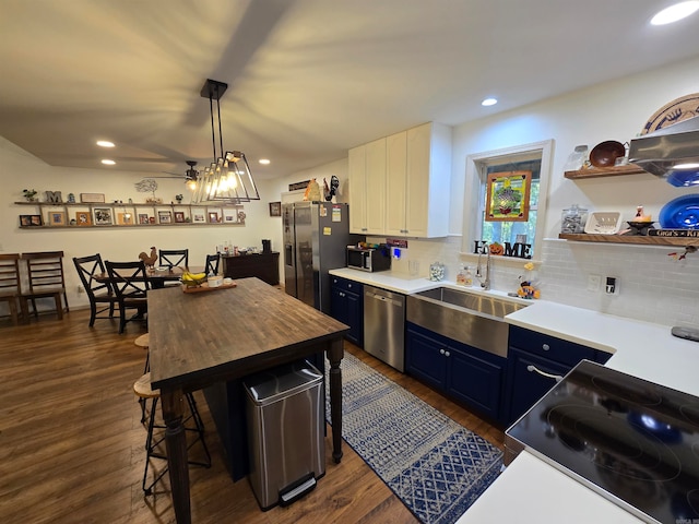 kitchen with sink, dark hardwood / wood-style flooring, blue cabinets, hanging light fixtures, and stainless steel appliances