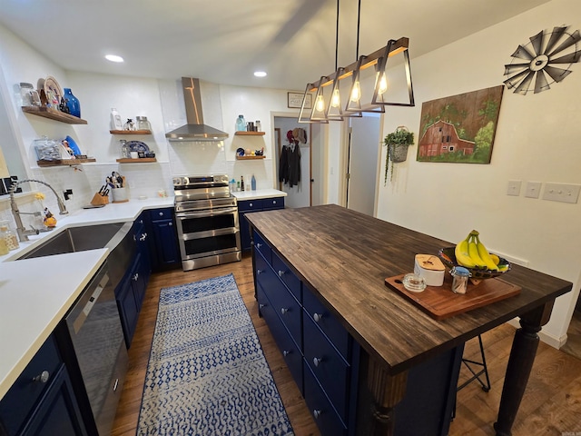 kitchen featuring sink, stainless steel appliances, wall chimney exhaust hood, wooden counters, and blue cabinetry