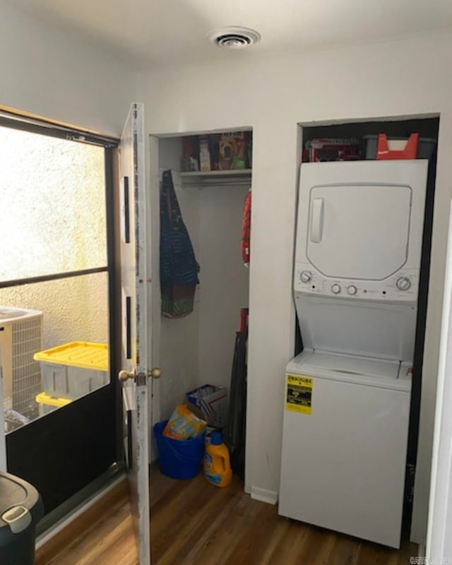 clothes washing area with stacked washing maching and dryer and hardwood / wood-style flooring