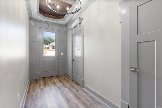 entryway with light hardwood / wood-style floors and a raised ceiling