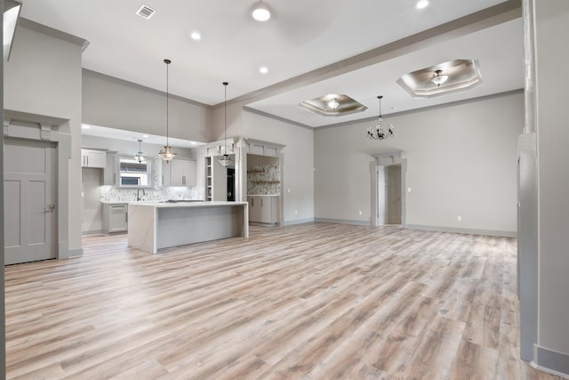 kitchen with sink, a center island, light hardwood / wood-style floors, decorative light fixtures, and ornamental molding