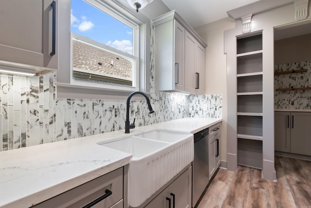 kitchen featuring wood-type flooring, sink, light stone countertops, gray cabinets, and stainless steel dishwasher