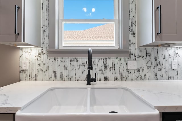 interior details with light stone counters, sink, and backsplash