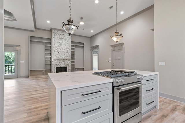 kitchen with stainless steel range, light hardwood / wood-style flooring, decorative light fixtures, white cabinets, and a fireplace