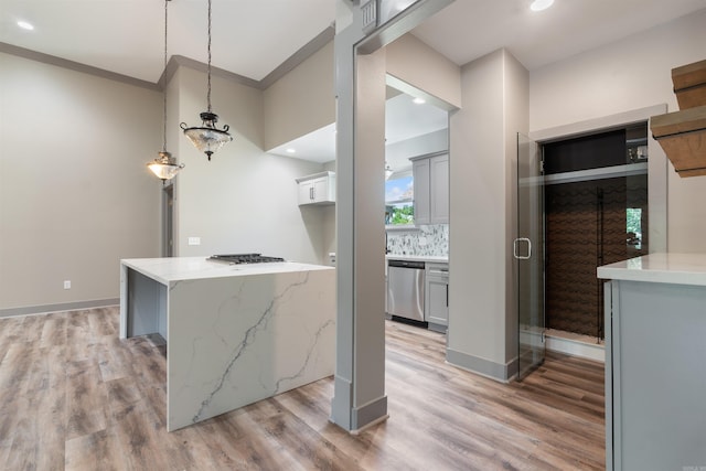 kitchen with crown molding, appliances with stainless steel finishes, decorative light fixtures, and light wood-type flooring