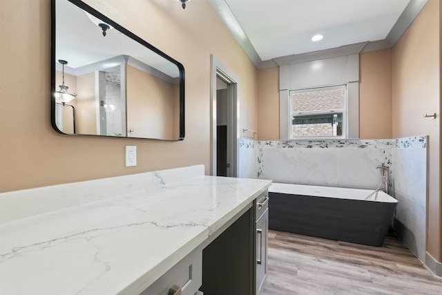 bathroom featuring tile walls, vanity, hardwood / wood-style floors, and a bathtub