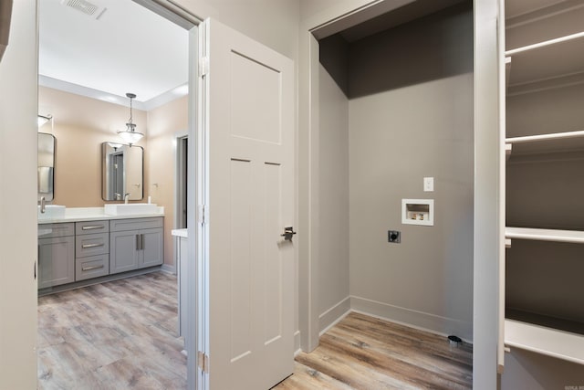 clothes washing area featuring hookup for an electric dryer, sink, washer hookup, and light wood-type flooring