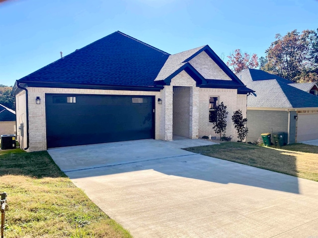 view of front of home with a front lawn, central AC, and a garage