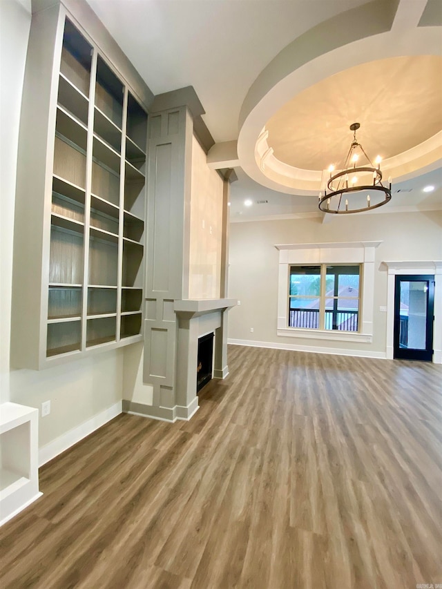 unfurnished living room with a notable chandelier, hardwood / wood-style floors, and a tray ceiling