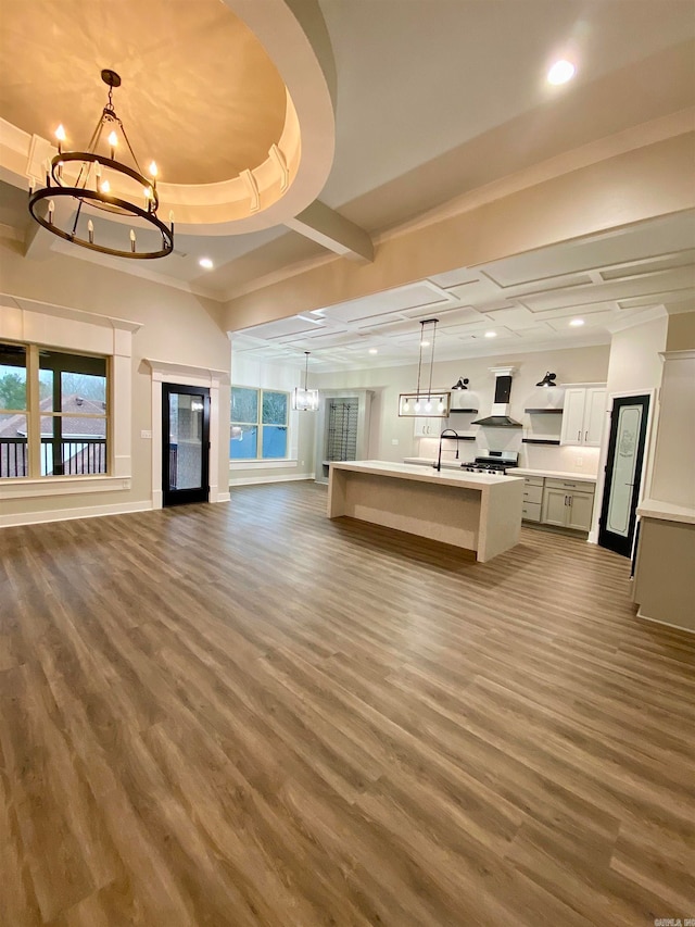 unfurnished living room with crown molding, a raised ceiling, dark hardwood / wood-style flooring, and an inviting chandelier