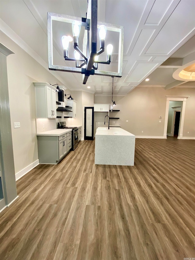 kitchen featuring sink, stainless steel gas stove, hardwood / wood-style floors, white cabinetry, and a notable chandelier