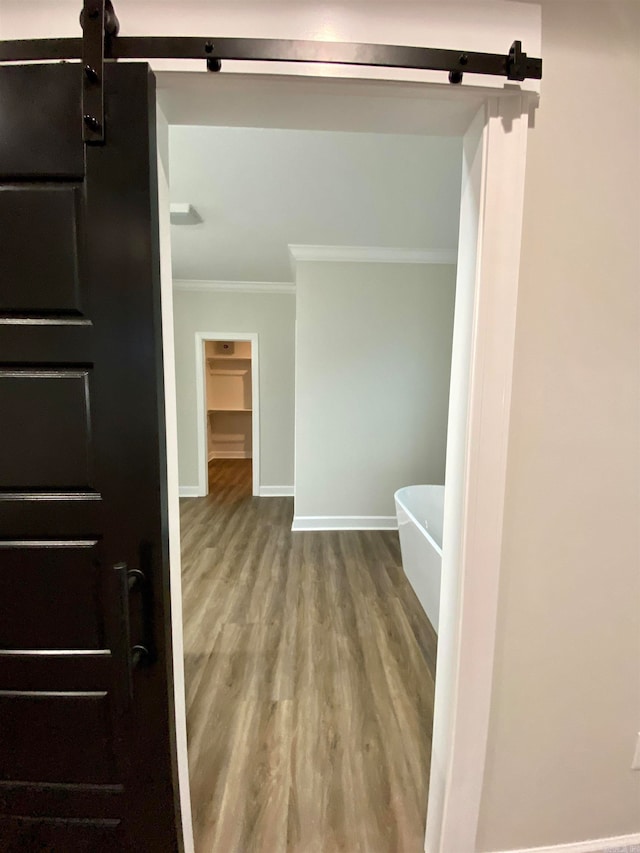 bathroom featuring ornamental molding, a tub to relax in, and wood-type flooring