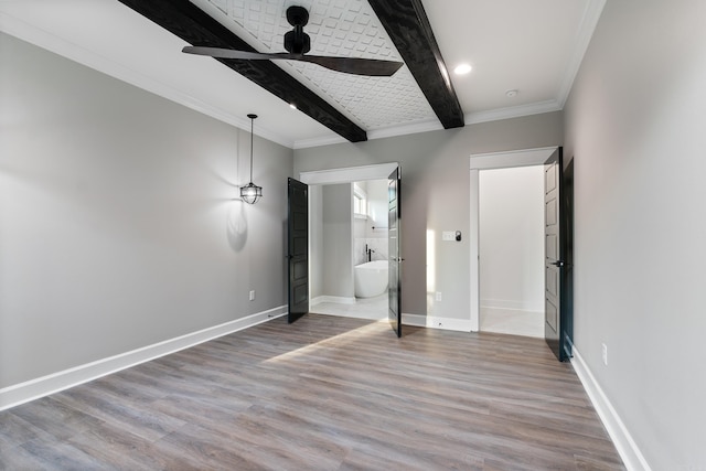 unfurnished bedroom with connected bathroom, beamed ceiling, ornamental molding, and hardwood / wood-style floors